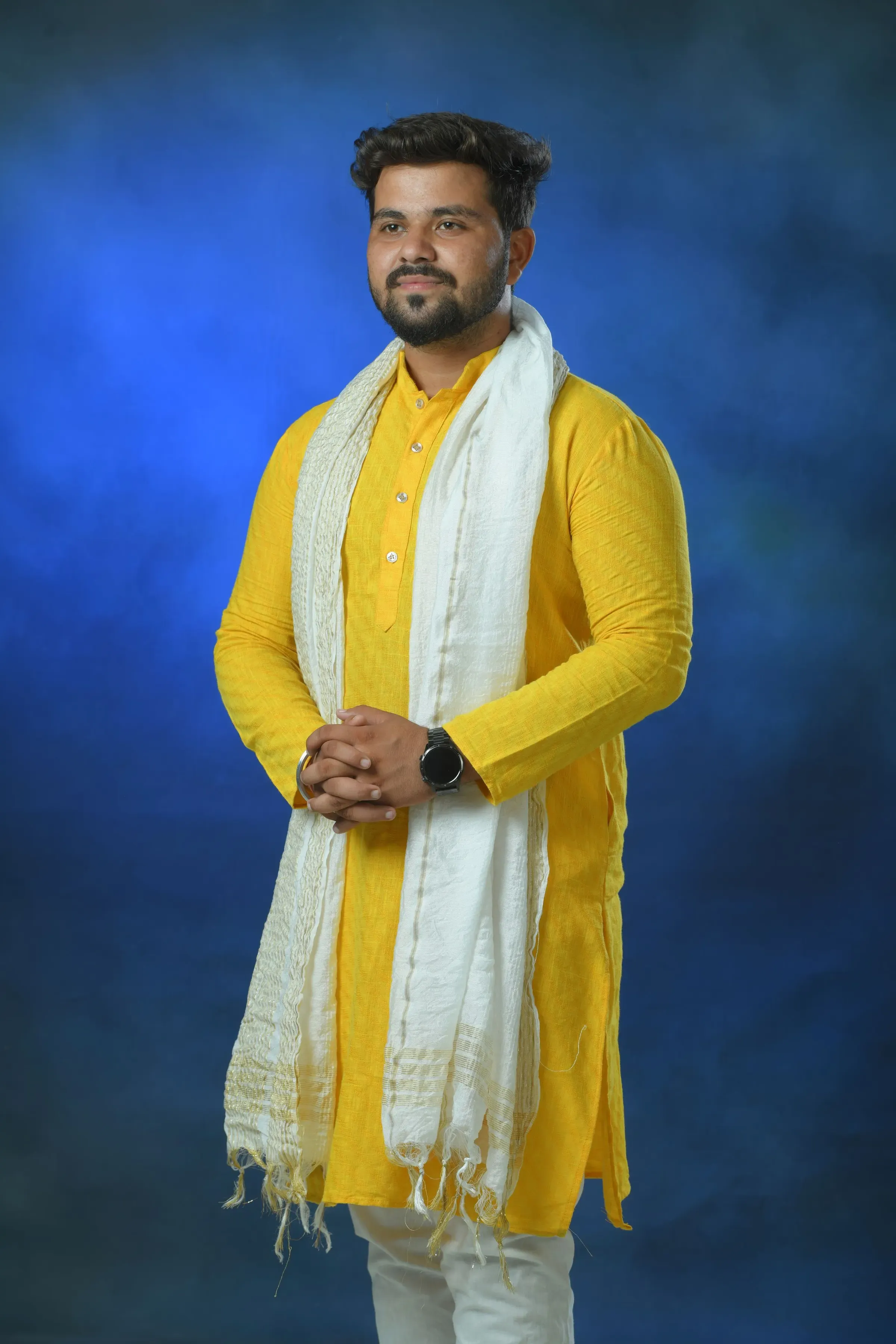 Man in a haldi yellow cotton kurta and ivory stole against an indigo backdrop